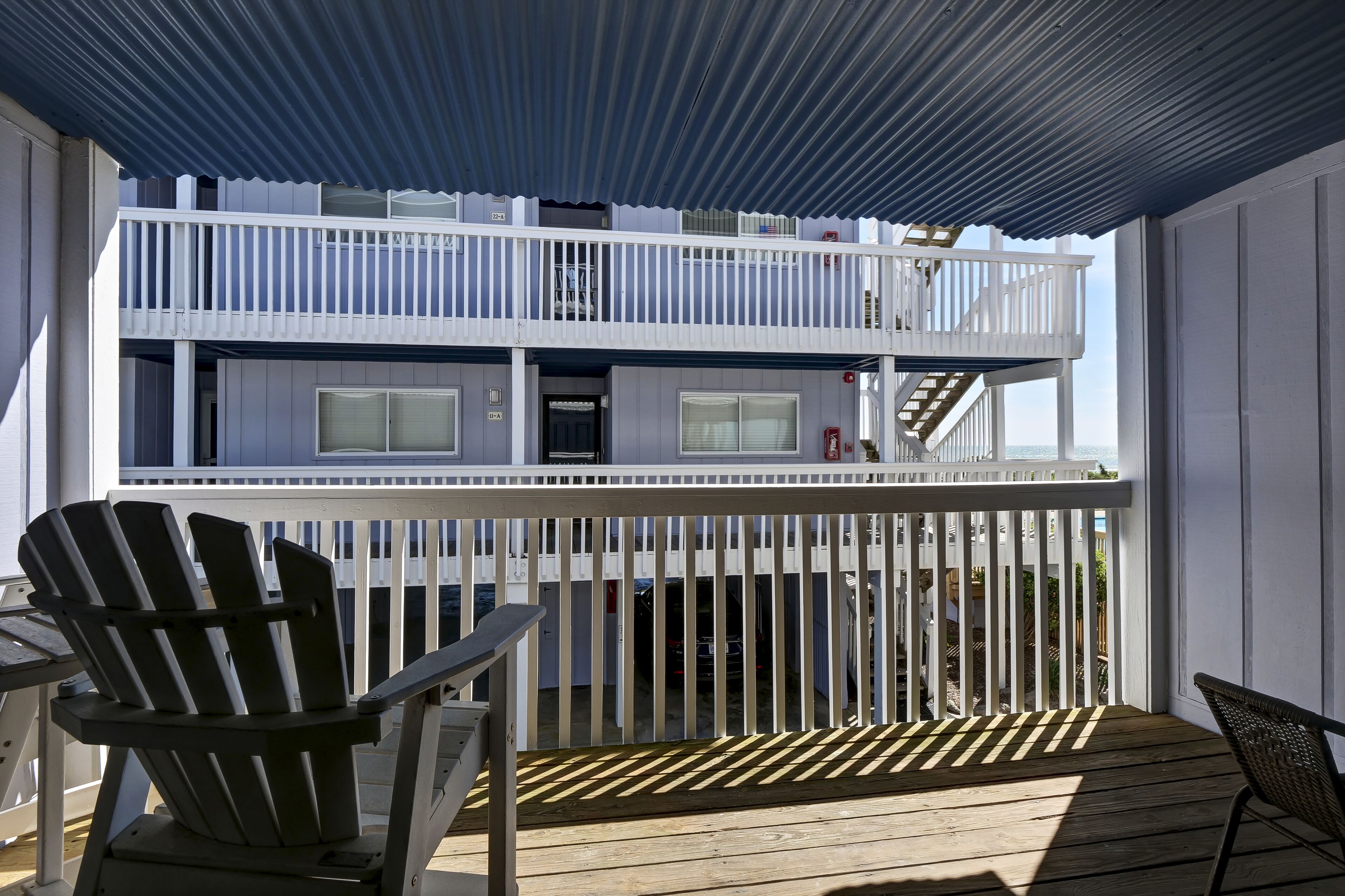 Um edifício de dois andares com varanda, deck coberto e vista para o oceano.