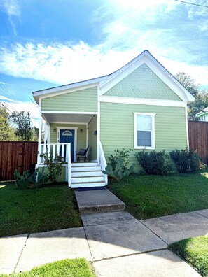 A single-story house with a front porch, a door, and a small window.