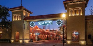 A historic hotel with a prominent archway entrance, a neon sign, and a street view with string lights.