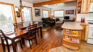 A cozy living room with a fireplace, wooden furniture, and a dining area with a table set for four. - Moose Meadows near Kilcher Homestead in Alaska the Last Frontier (Homer)