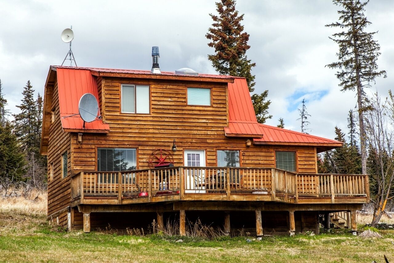 Una cabaña de madera con techo rojo, un balcón y una antena parabólica.