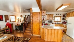 A spacious kitchen with wooden cabinets, a central island, and a staircase leading to another level. - Moose Meadows near Kilcher Homestead in Alaska the Last Frontier (Homer)