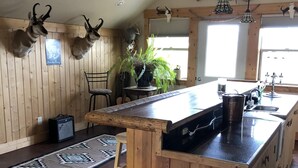 Cozinha com ilha de madeira, ventilador de teto, chifres de veado na parede e janela com vista.