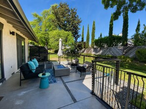 An outdoor patio with a seating area, including a sofa and chairs, a small table, and a fire pit.