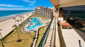 A hotel balcony with a view of the beach and a pool area.
