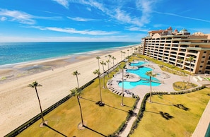 Ein Resort mit Strand, Poolbereich und einem großen Gebäude mit mehreren Balkonen.