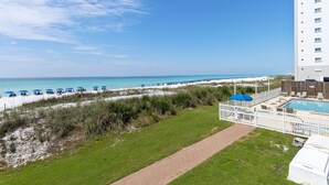 Un hôtel situé en bord de mer, doté d’une piscine, de parasols et offrant une vue dégagée sur l’océan.