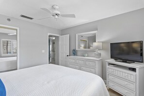 Une chambre à coucher comprenant un lit, un téléviseur, une commode et un ventilateur de plafond.