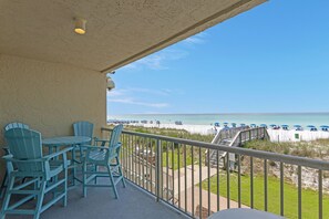 Un balcon avec vue sur la plage, des sièges d’extérieur et une rambarde.