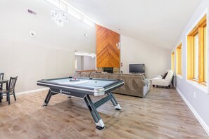A spacious living area with a pool table, a fireplace, and a television.