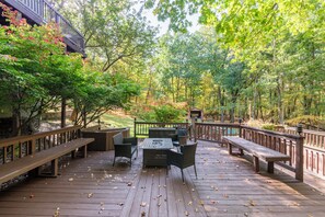A wooden deck with outdoor furniture, surrounded by trees and a wooden fence.