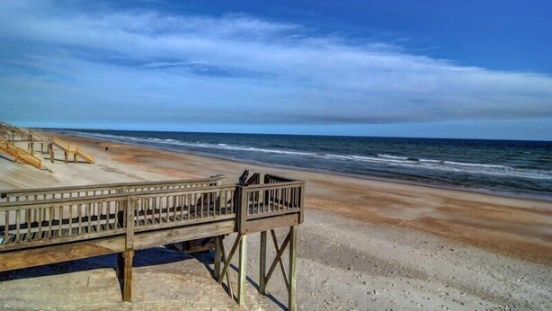 A wooden boardwalk leading to a beach with a clear sky. - Sassy Seahorse | Pet Friendly + Near Area Fun! (Surf City)
