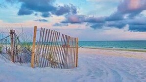 Een strand met een houten omheining en een heldere lucht.