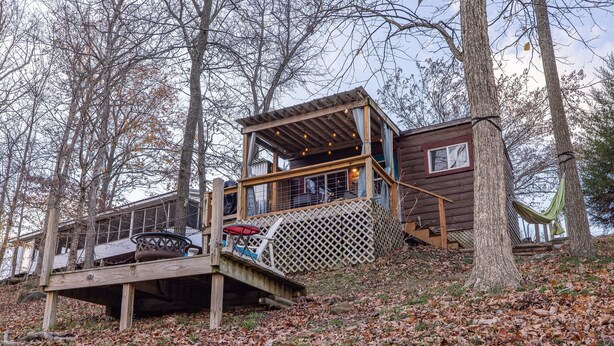 A cabin with a deck, a covered porch, and a window overlooking the forest.