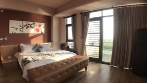 Un dormitorio amplio con una cama grande, una zona de estar y un balcón con cortinas.