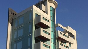 Un moderno edificio de gran altura con varios balcones, ventanas amplias y una sección superior curva distintiva.