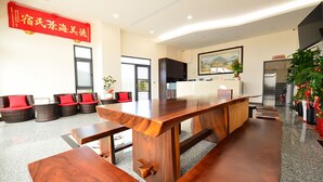 Un moderno vestíbulo de hotel con un largo mostrador de recepción de madera, áreas de estar cómodas y un gran cartel rojo con caracteres chinos.
