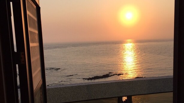 Un balcón con vista al océano al atardecer.