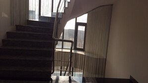Una escalera con barandilla de metal que lleva a un rellano con vistas al exterior.