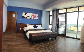A modern hotel room with a large bed, a blue accent wall, and a view through a sliding glass door. - Cimei Deemei (Qimei)