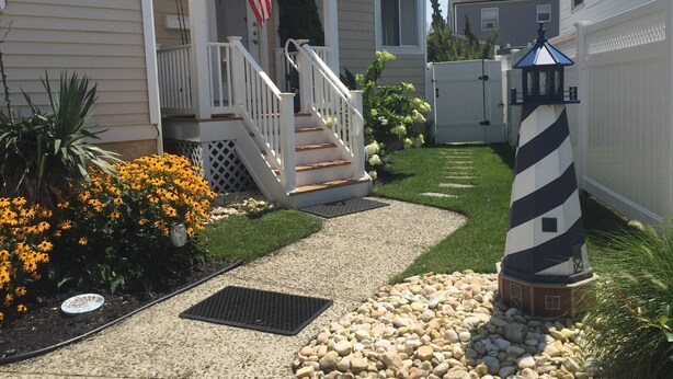 A residential property with a front porch, a small staircase, a pathway leading to the entrance, a decorative lighthouse, and a well-maintained lawn. - 5 Star AMAZING Perfect Beach Retreat just for you.  Cozy, Clean, Comfortable (Brigantine)