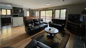 Un salón amplio con chimenea, sofás de cuero, una mesa de centro y un televisor.