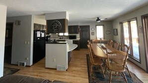 Una cocina amplia con una isla central, un comedor con sillas de madera y grandes ventanales que ofrecen luz natural.