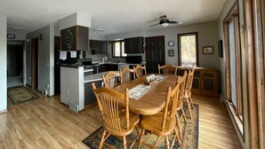 Una cocina amplia con electrodomésticos modernos, un comedor con sillas de madera y un gran ventanal que proporciona luz natural.