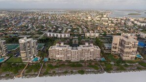 Un paysage urbain côtier avec un hôtel imposant, doté de plusieurs étages, d’une piscine et donnant sur la plage.