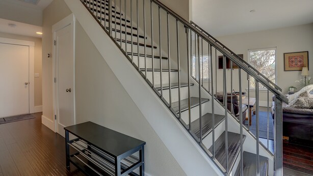 A staircase with metal railings and a dark wooden table at the bottom. - Surfsup - Downtown, River View, A/C, Stay for a Month! Great Rates! (Hood River)