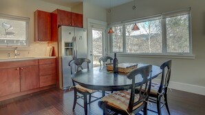 A modern kitchen with wooden cabinets, a stainless steel refrigerator, and a dining table with chairs. - Surfsup - Downtown, River View, A/C, Stay for a Month! Great Rates! (Hood River)