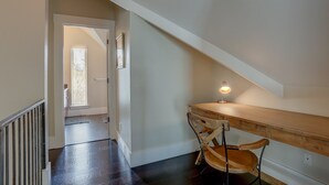 A hallway with a wooden desk and chair, a light fixture, and a door leading to another room. - Surfsup - Downtown, River View, A/C, Stay for a Month! Great Rates! (Hood River)