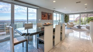 A modern dining area with a glass table, white chairs, and a view of the cityscape. - Scottsdale Manor - 9BR Estate w/ Infinity Pool, Theater & Mountain Views (Phoenix)