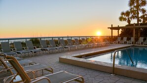 Zona junto a la piscina con sillones de descanso y piscina al atardecer.