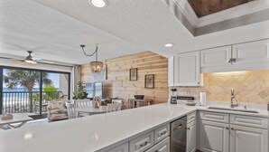 Una cocina moderna con armarios blancos, una isla grande y vista a la playa.
