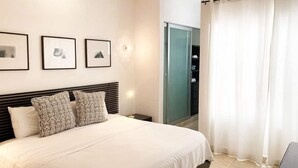 A hotel room with a bed, a nightstand, a wall-mounted lamp, and a sliding door leading to a bathroom. - Beach 1 Block, 2BR, Garage, Roof Pool, L3 (Playa del Carmen)