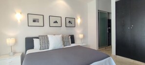 A modern bedroom with a large bed, two bedside lamps, and three framed pictures on the wall.