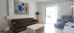 A living room with a sofa, a coffee table, a lamp, and a painting on the wall.