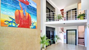 A hotel lobby with a large painting, a staircase, and an elevator. - Beach 1 Block, 2BR, Garage, Roof Pool, L3 (Playa del Carmen)