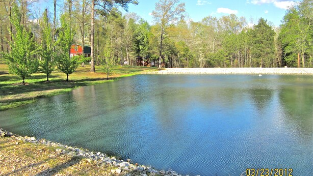 A calm lake surrounded by trees and a red building. - Cabin # 2, Kentucky Lake, Bass Fishing, Camden, Tn, (Nashville 1, Memphis 1.5) (Camden)