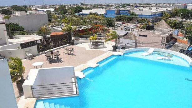 A rooftop pool with a clear view of the surrounding cityscape, including a Walmart store. - 2BR, Central, Sleeps 6, Garage, Roof Pool, A306 (Playa del Carmen)