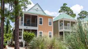 A two-story house with a green roof, a balcony, and a porch. - Tranquil Paradise: Luxury Vacation Home Offering Amazing Pools Near Beach (Pensacola)