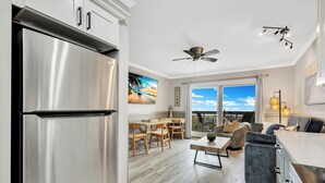 Una cocina moderna con un refrigerador de acero inoxidable, un comedor con mobiliario de madera y un balcón con vistas.