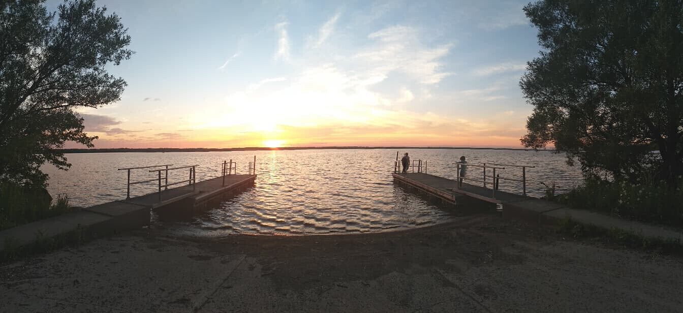 A pier extending into a calm body of water during sunset.