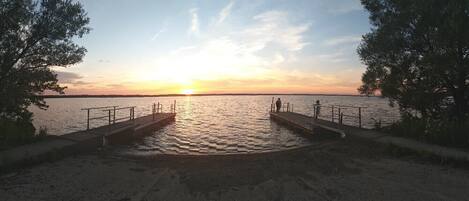 A pier extending into a calm body of water during sunset.
