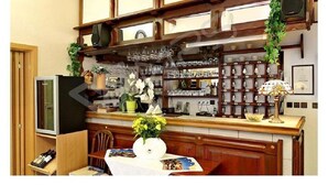 A kitchen with wooden cabinets, a refrigerator, a dining table with chairs, and a variety of kitchenware on shelves. - Hotel Rajsky (Cesky Krumlov)