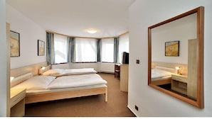A hotel room with two beds, a desk, a chair, a television, and a large mirror. - Hotel Rajsky (Cesky Krumlov)