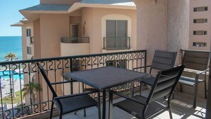 Un balcon avec une table et des chaises, donnant sur une piscine et un immeuble doté de balcons.