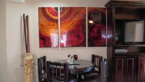 Un coin repas avec une table ronde, des chaises en bois foncé et un vase contenant des tiges de bambou.