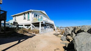 Ein Strandhaus mit Veranda und einer Treppe zum Eingang.